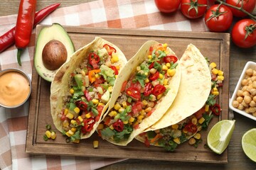 Tasty vegetarian tacos with chickpeas, corn and quinoa served on wooden table, flat lay