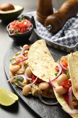 Tasty vegetarian tacos with beans and quinoa served on grey table, closeup