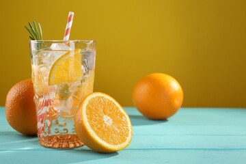Refreshing soda water with ice and orange on light blue wooden table, closeup. Space for text