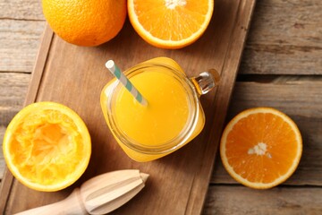 Tasty orange juice in mason jar, fresh fruits and juicer on wooden table, flat lay