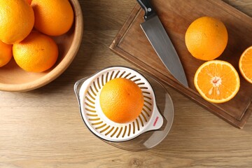 Making juice. Juicer, fresh oranges and knife on wooden table, flat lay