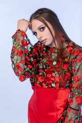 A stunning fashion model graces the scene in a vibrant floral outfit that features red accents