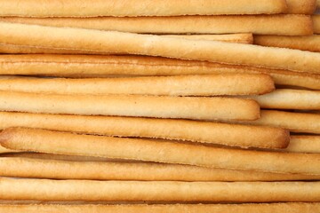 Delicious grissini sticks as background, top view