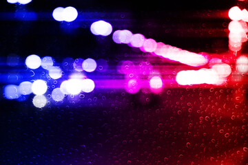 Police red and blue lights in city at night, blurred view through wet glass