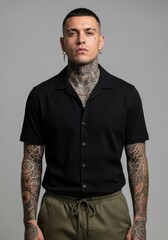 Obraz premium A portrait of a person with intricate tattoos and stylish short-sleeved shirt. The individual's intense gaze adds a sense of depth