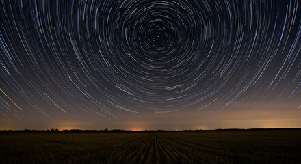 Star trails over a dark field with a horizon line and a circular pattern of light streaks in the sky