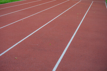 Fototapeta premium An empty red running track with white start and finish lines at an outdoor athletic stadium, a background with copyspace, concept of sports, competition, motivation.