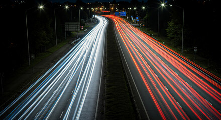Obraz premium Traffic light trails on a highway at night with streetlights and dark surroundings in a long exposure
