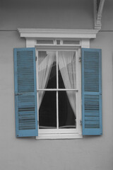 Decorative exterior outside window with turquoise shutters.