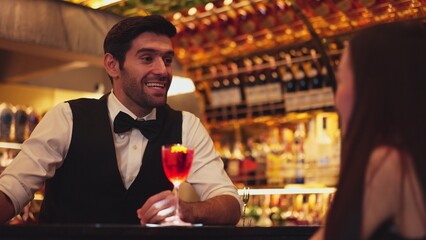 Bartender serving mixed vodka Cosmopolitan red cocktail decorated with flower for beautiful guest at luxurious counter bar perfect vibrant color presentation highlight atmosphere nightclub. Vinosity.