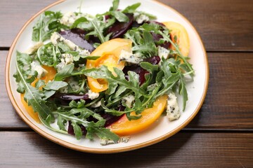 Tasty salad with arugula, blue cheese and vegetables on wooden table, closeup