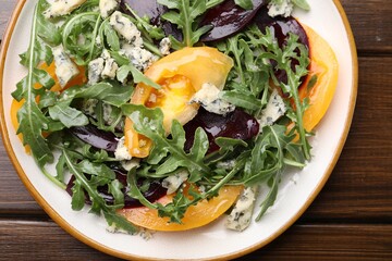 Tasty salad with arugula, blue cheese and vegetables on wooden table, top view