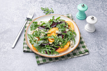 Tasty salad with arugula, blue cheese and vegetables on grey textured table