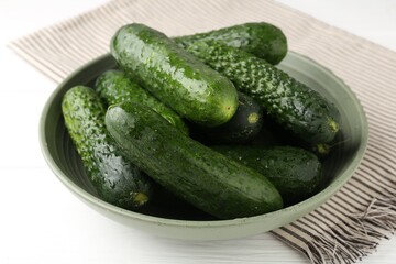 Fresh cucumbers in bowl on white wooden table, closeup