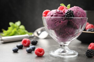 Delicious sorbet with fresh berries and mint in dessert bowl on grey textured table against dark background, closeup