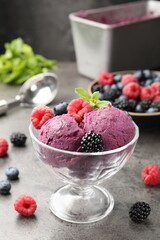 Delicious sorbet with fresh berries and mint in dessert bowl on grey textured table against dark background, closeup