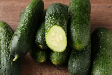 Whole and cut cucumbers on wooden table, closeup