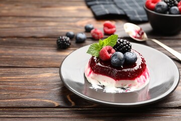 Delicious panna cotta with berries, jam and mint on wooden table, closeup