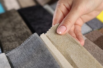 Woman choosing fabric among different samples indoors, closeup
