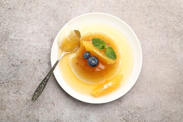 Tasty panna cotta with orange, blueberries and mint on light grey table, top view