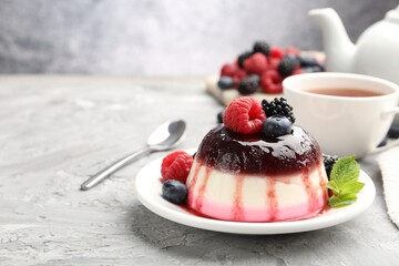 Tasty panna cotta with berries and jam on light grey table, closeup. Space for text