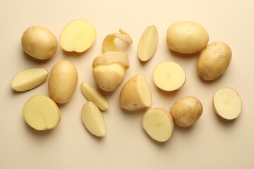 Fresh raw potatoes on beige background, flat lay