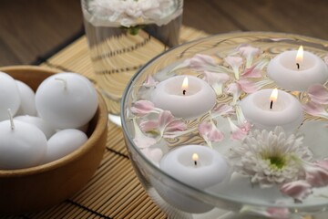 Bowl with water, candles, flowers and petals on table, closeup