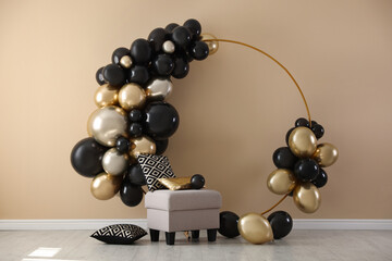 Stylish photo zone with balloons and pouf near beige wall