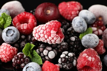 Many different frozen berries and mint on table, closeup