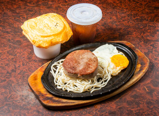 Juicy Filet Mignon with Noodles and Fried Egg on a Hot Plate side view of hong kong food