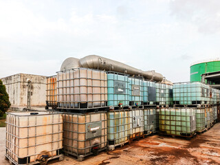 Outdoor Industrial Area with Stacked Intermediate Bulk Containers and Metallic Piping System under a Cloudy Sky Featuring Chemical Storage and Logistics Management in Global Industry Sector