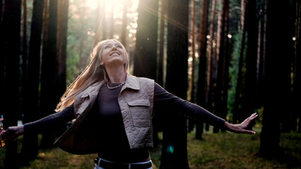 Hippie woman spinning around and enjoying life with a smile on her face outdoors in the forest. Beautiful caucasian woman relaxing in nature