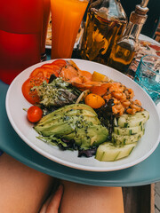 Colorful vegan salad with avocado, chickpeas, tomatoes, and cucumbers served outdoors.