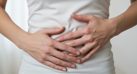 A person in a white shirt holds their abdomen with both hands