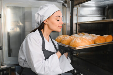 Baker smelling freshly baked bread coming out of the oven
