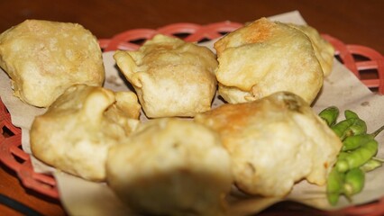 Traditional Indonesian snack of crispy fried tofu on a woven tray.