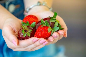 Obraz premium The most perfect sweet in the world, the iconic dessert strawberry of love on a stick, fresh strawberry, powdered milk brigadeiro and red caramel topping. Morango do amor