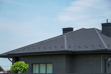 Modern black roof design enhances the curb appeal of a contemporary house in a suburban neighborhood on a clear day