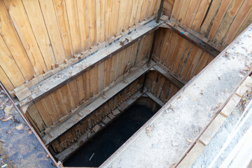 Deep construction pit with wooden supports located in urban area during daylight hours