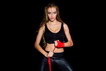Female boxer wrapping hands with red boxing bandages. Women self defense. Young athletic female MMA fighter in sport protective bandages. Sporty sexy girl ready for fight or sparring. Active exercise.