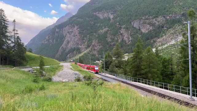 Train and Jungfrau mountains in background, Red modern passenger train is moving on railway in swiss alps, Landscape with train in high mountains, Bernina Express, Switzerland. Mauntain pass