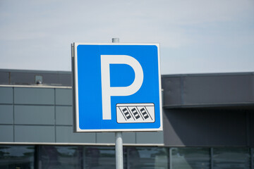 Parking sign with clear blue background near modern building during daytime in urban area