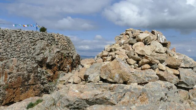 Obo (ovoo - sacred heap of stones) on top of the hill against the backdrop of picturesque cloudy sky. Mongolia.