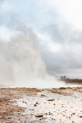 Strokkur geyser in Haukadalur valley after eruption on a rainy April day.
