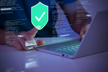 Person using a laptop with a glowing security shield and checkmark icon, symbolizing cybersecurity, data protection, encryption, and safe digital operations in a connected world.