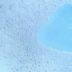 Macro close-up of tiny blue bubbles clustered together, creating a textured foam-like surface with a soft water gradient in the background