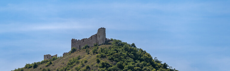 Fototapeta premium Ruins of a castle on a hill with blue sky in the background. 