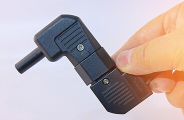 The hand holds the electrical connectors. Close-up. Soft focus. 