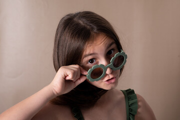 Girl model in green glasses on beige background. Portrait of fashion girl model in stylish sunglasses.