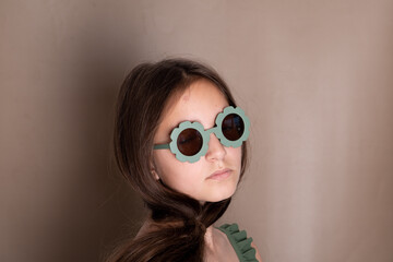 Girl model in green glasses on beige background. Portrait of fashion girl model in stylish sunglasses.